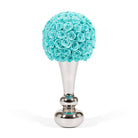 Decorative object with turquoise rose ball on a silver stand against a white background