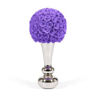Purple floral arrangement on a silver stand against a white background