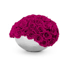 White spherical vase filled with bright pink roses on a white background