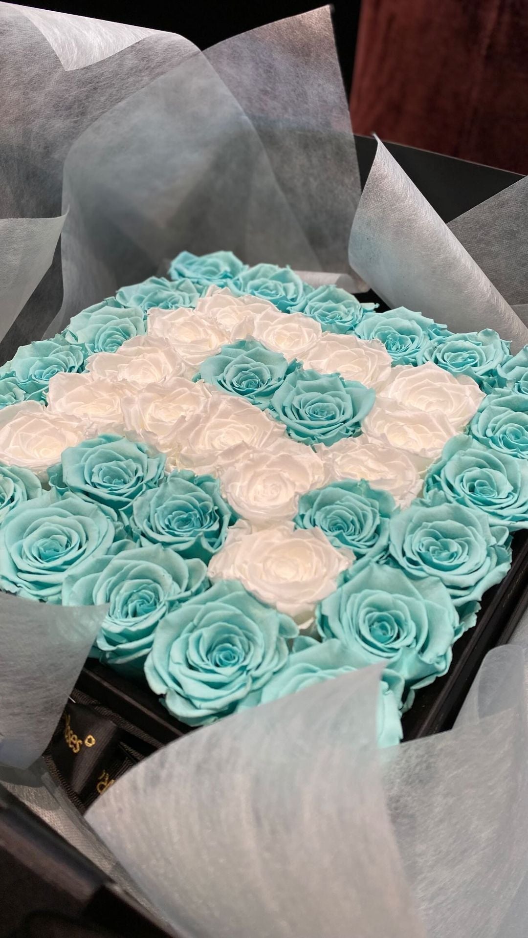 Bouquet of turquoise and white roses arranged in a diamond pattern.