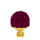 Bouquet of dark red roses on a gold pedestal against a white background