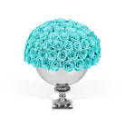 Bouquet of turquoise roses in a silver vase on a white background