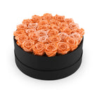 Black round box filled with orange roses on a white background