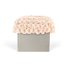 Floral arrangement with pink roses on a gray box against a white background