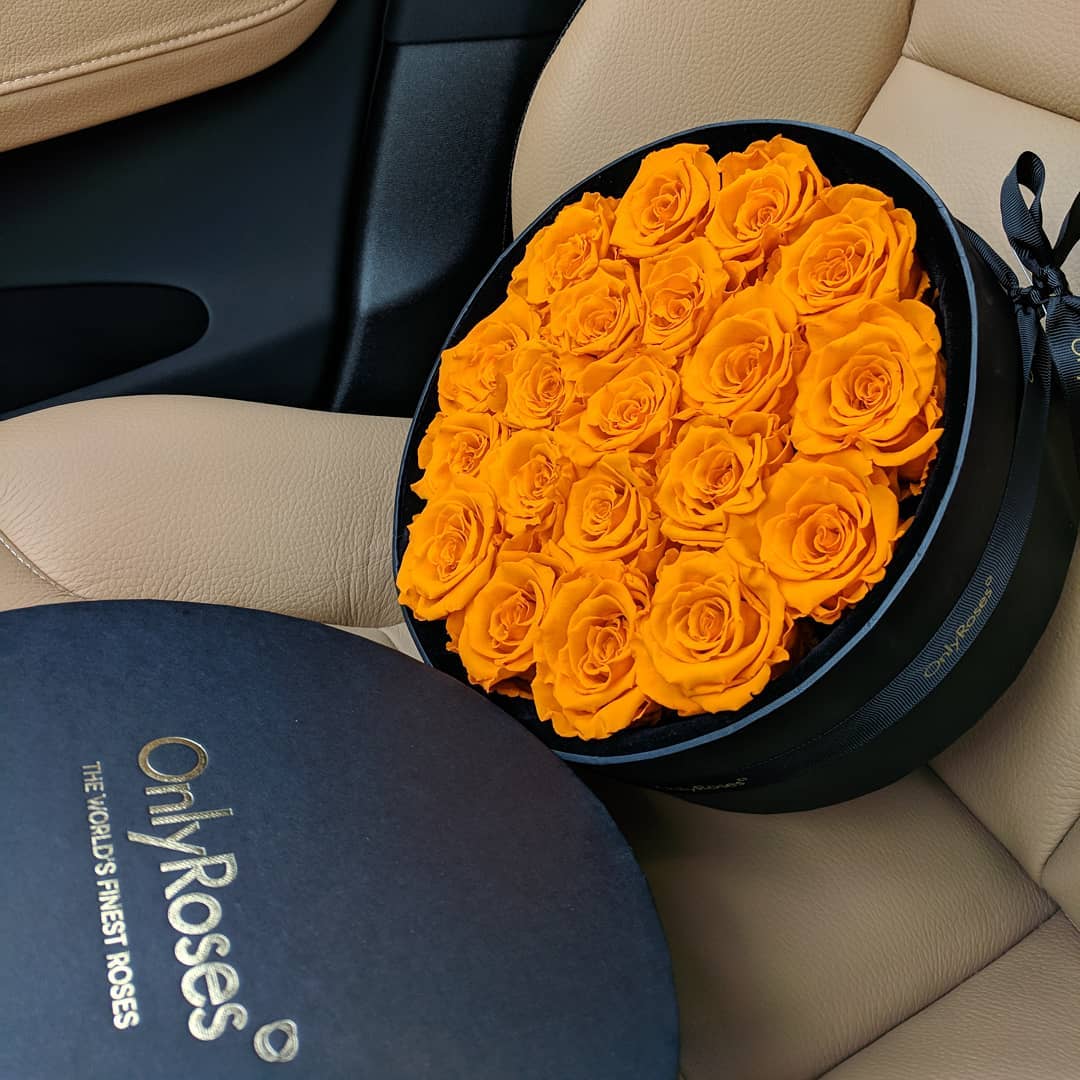 Round black box with yellow roses on a car seat, featuring 'Only Roses' branding.